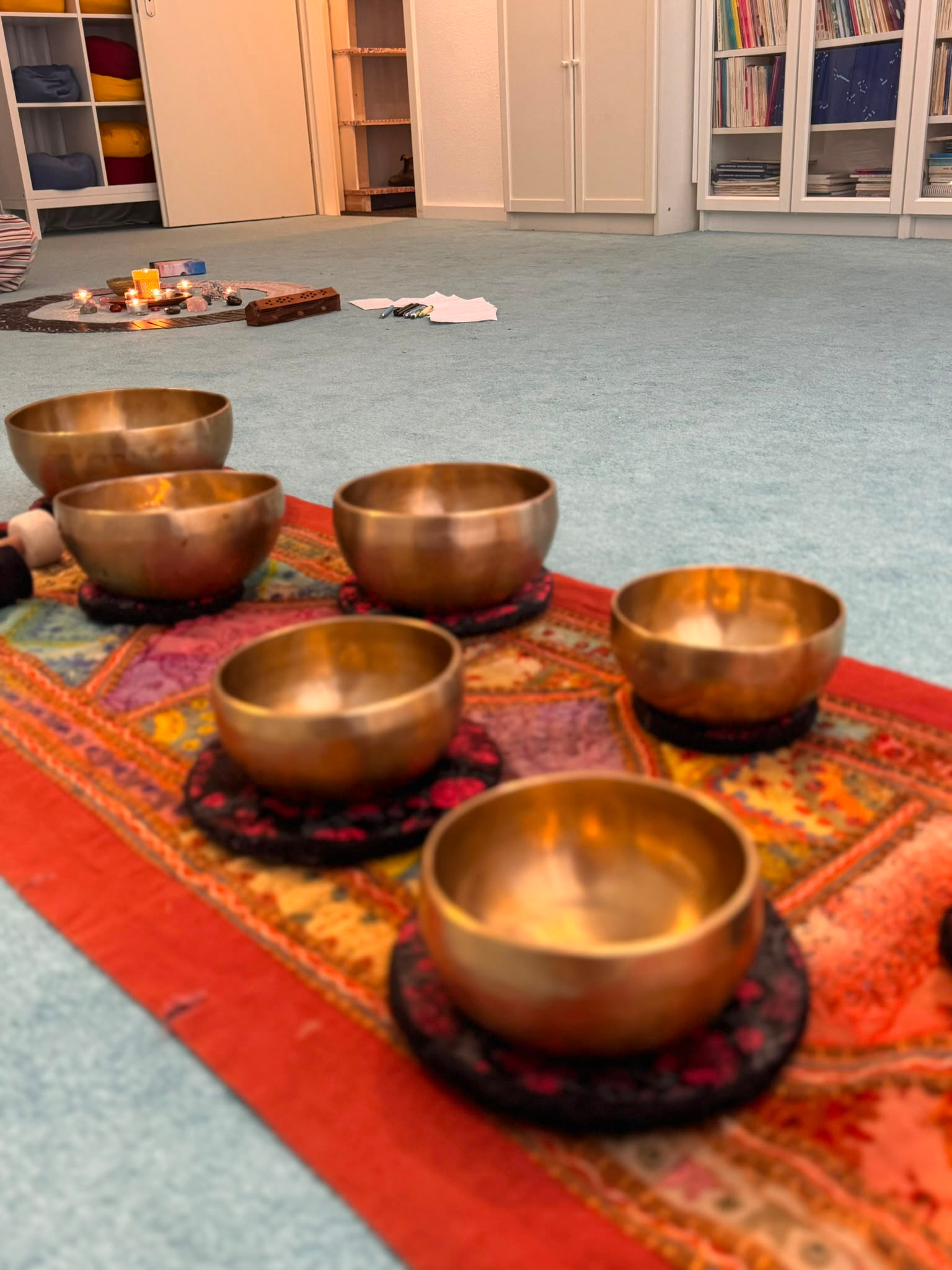 Tibetan singing bowls arranged in a candlelit circle, ready for a sound bath